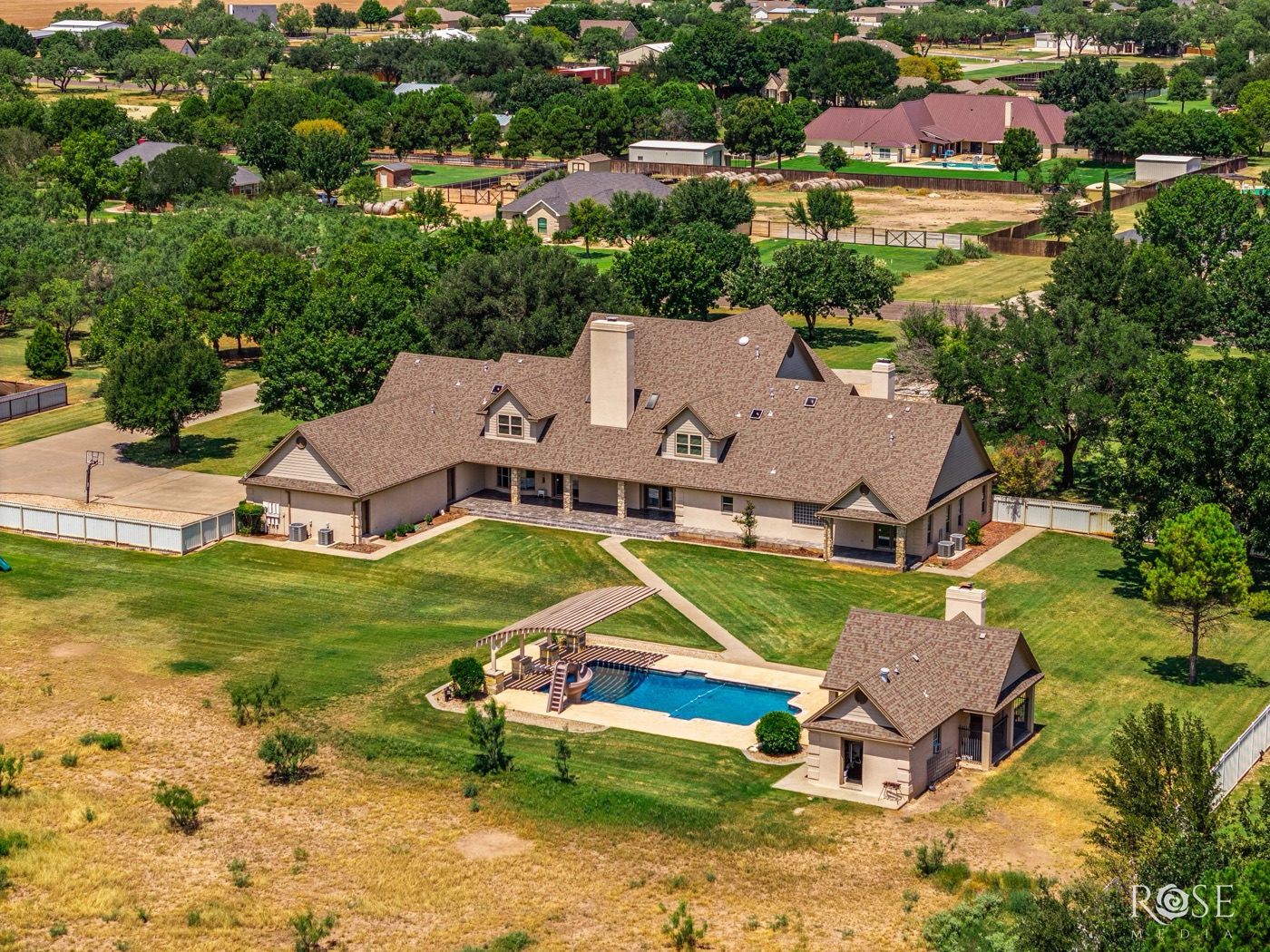 Aerial view of a large estate home with a pool on a golf-course lot in San Angelo